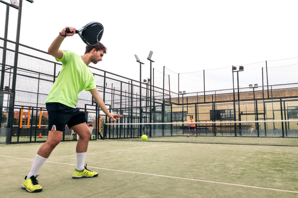 young man serving in a paddle tennis game